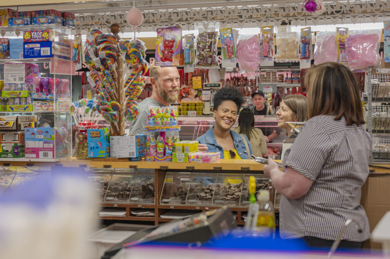 A couple who joined Flamboyance Tours having a chat with the stall operator of Blackeby's at the Adelaide Central Market