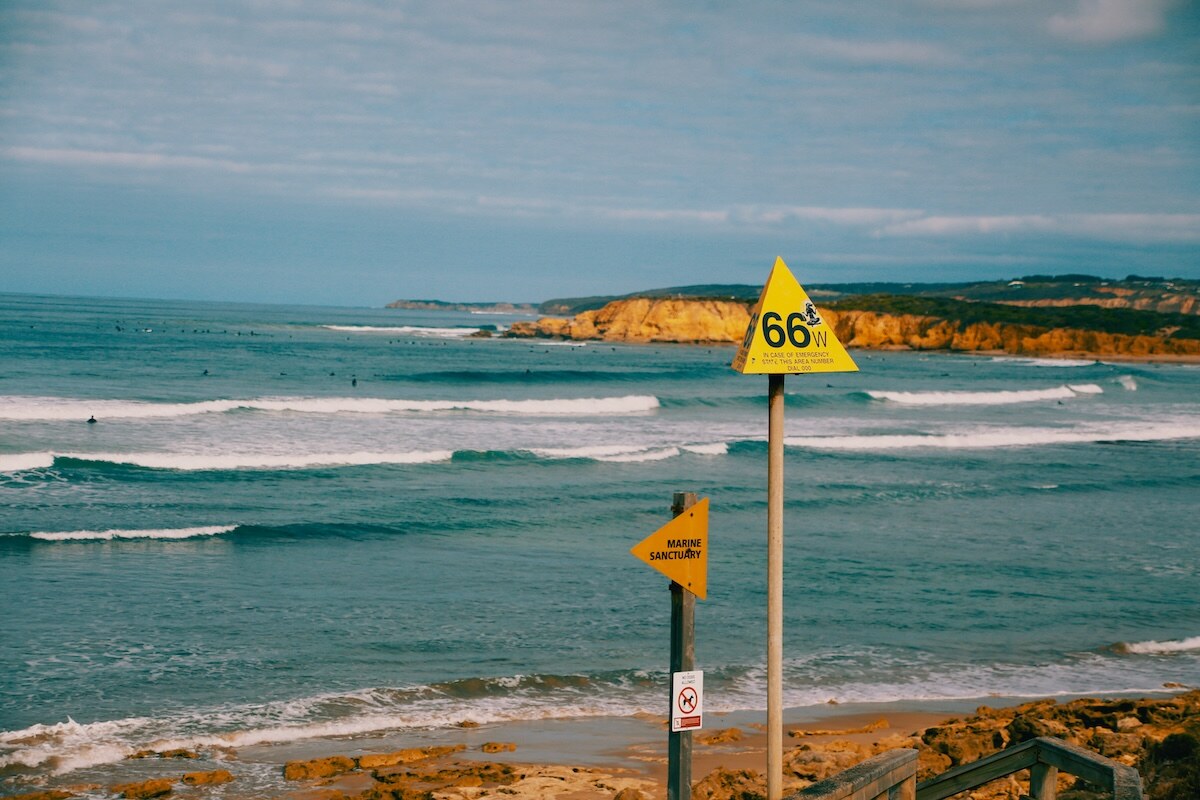 Beach signs with surfers in the background in Torquay